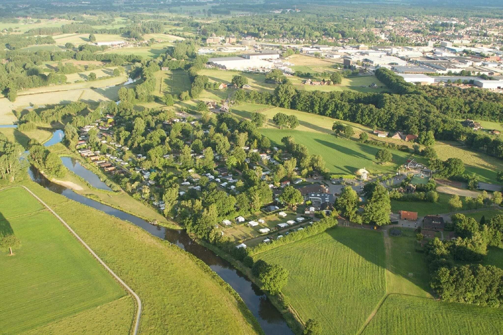 An aerial view of a residential area with houses, a river, and surrounding greenery.