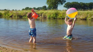 Twee kinderen spelen met een strandbal in een ondiepe rivier.