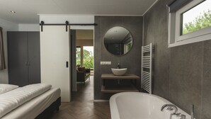 Een moderne badkamer met een vrijstaand bad, een ronde spiegel en een inbouwwastafel.