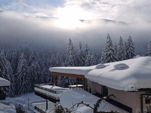 Un paisaje nevado con un edificio que tiene un balcón y un espacio al aire libre cubierto.