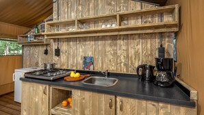 Una cocina con armarios de madera, encimera negra, estufa, fregadero y cafetera.