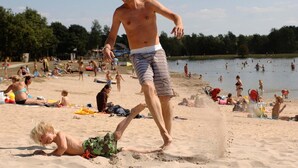 Une scène de plage où l’on voit des gens se prélasser au soleil et nager.