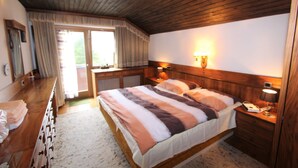 Ein Schlafzimmer mit Holzboden, einem großen Bett mit gestreifter Bettwäsche, einem Nachttisch mit Lampe und einem Fenster mit Vorhängen.