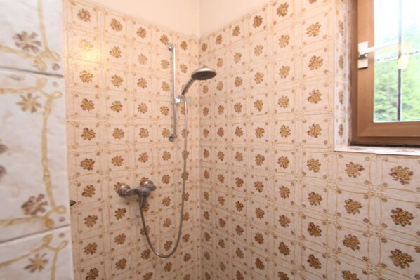 A shower with a floral tile pattern and a window with a view of greenery. - Holiday home in Innerkrems in Carinthia with sauna (Innerkrems)