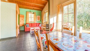 A cozy room with a wooden ceiling, a sofa, a table, and a fireplace. - Holiday home with terrace (Lage Zwaluwe)