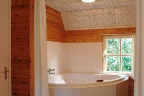A bathroom with a freestanding bathtub, wooden ceiling, and a window with a view of greenery. - Farmhouse in Herperduin with Bubble Bath (Herpen)