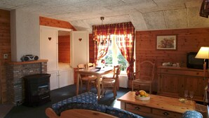 A cozy cabin interior with a dining area, a sofa, a fireplace, and a television. - Farmhouse in Herperduin with Bubble Bath (Herpen)