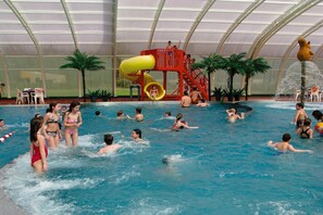 An indoor swimming pool with a water slide and palm trees. - Farmhouse in Herperduin with Bubble Bath (Herpen)