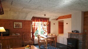A cozy cabin interior with a dining area, a sofa, a television, and a fireplace. - Farmhouse in Herperduin with Bubble Bath (Herpen)