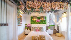 Une chambre avec un grand lit, un mur vert orné de plantes et un plafond décoré de fleurs.