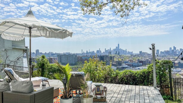 Une terrasse sur le toit, aménagée avec du mobilier d’extérieur, une statue d’éléphant décorative et une vue sur le paysage urbain.