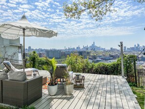 Una terrazza sul tetto con mobili da esterno, una statua decorativa a forma di elefante e vista sulla città.
