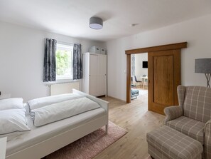 Une chambre comprenant un lit, une chaise, une armoire et une porte donnant sur un coin repas.