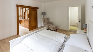 A bedroom with a bed, a chair, a wardrobe, and a door leading to a bathroom.