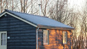 A small wooden cabin with a sloped roof and a chimney. - Cozy vacation home with terrace (Lage Zwaluwe)