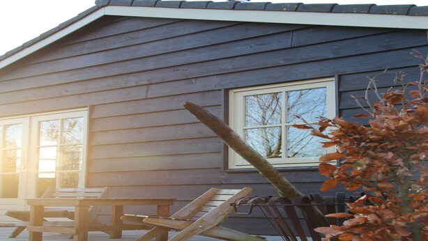 A wooden house with a porch, a table, and chairs. - Cozy vacation home with terrace (Lage Zwaluwe)