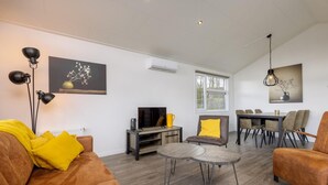 Een moderne woonkamer met een bank, salontafel, televisie en een eethoek.