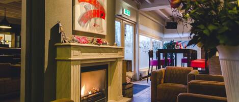A cozy lobby with a fireplace, comfortable seating, and a large window offering a view of the outdoors.
