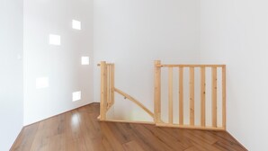 Ein Zimmer mit Holzboden, weißen Wänden und einer Holzwand mit vertikalen Lamellen.