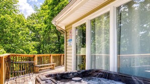 A hot tub on a wooden deck with a view of trees.