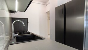 A modern kitchen with a stainless steel refrigerator, a black sink, and a sleek countertop. - Apartment Zora - 
Charming 2-bedroom apartment with AC, WiFi in amazing Pula (Pula)
