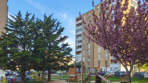 A playground with slides and climbing structures, surrounded by a fenced area with a tree and grass. - Apartment Zora - 
Charming 2-bedroom apartment with AC, WiFi in amazing Pula (Pula)