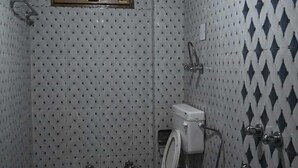 A small, tiled bathroom with a toilet, bidet, and shower. - Taj Guest House (Manali)