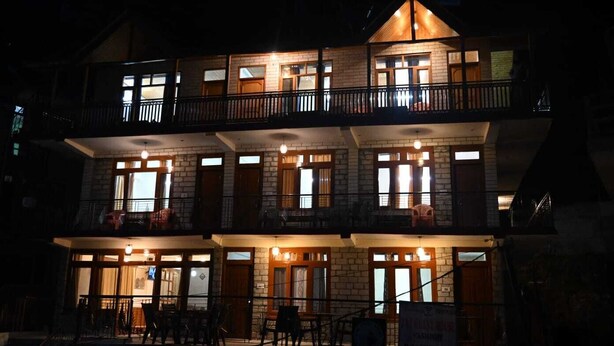 A multi-story building with a balcony on the second floor, large windows, and a staircase leading to the upper levels. - Taj Guest House (Manali)