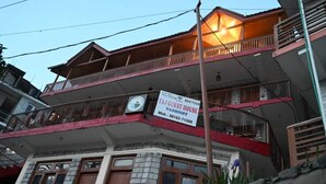 A multi-story building with a sign for 'TAJ GUEST HOUSE' and a contact number. - Taj Guest House (Manali)