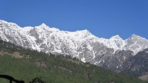 A mountain range with snow-capped peaks and a forested valley. - Taj Guest House (Manali)