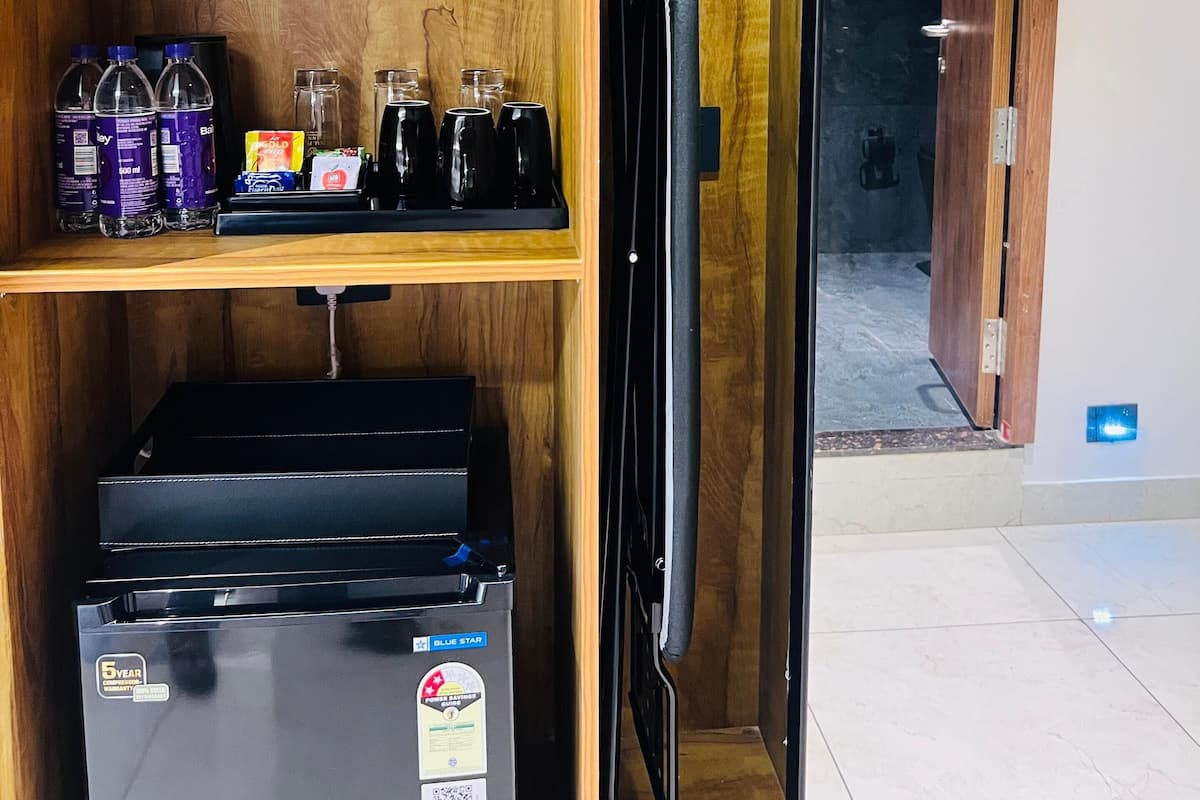 Una cocina compacta con refrigerador, un lavamanos y estantes de madera con diversos objetos.