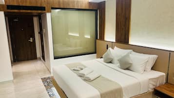 Habitación de hotel moderna con una cama grande, una mesita de noche, un ventanal amplio y un revestimiento de pared de madera.