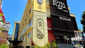 Hotellin yläpuolella oli suuri, huomiota herättävä kyltti, jossa luki: ”ROYAL PLAZA INN RUKZAR”.