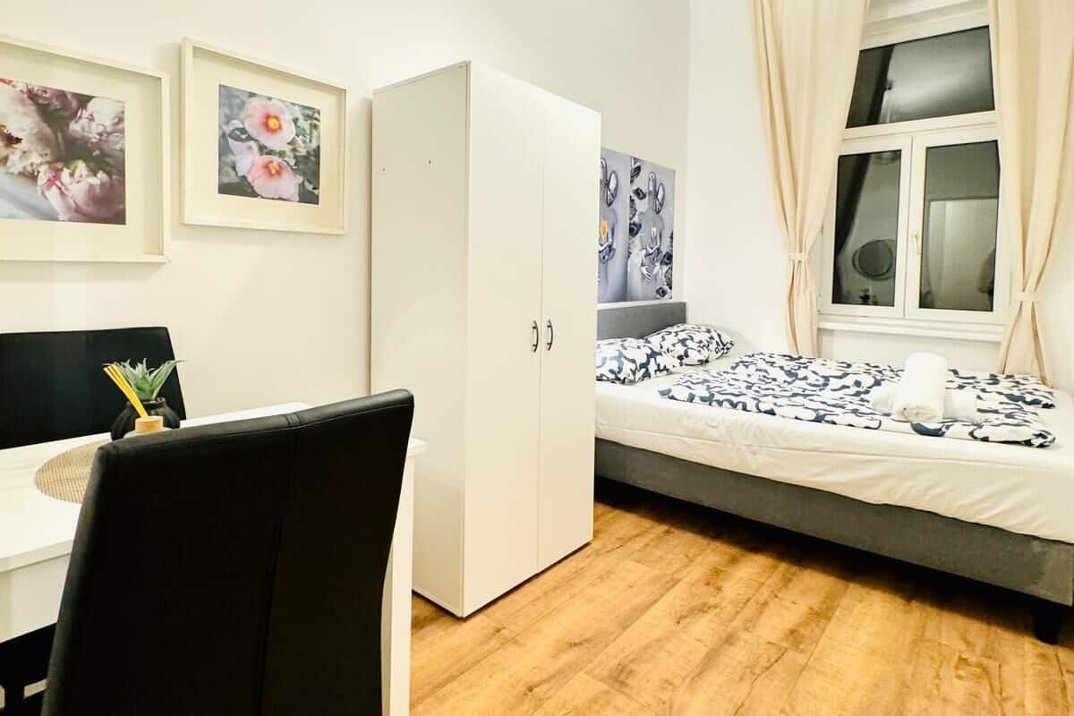 A modern bedroom with a bed, a desk, and a wardrobe.