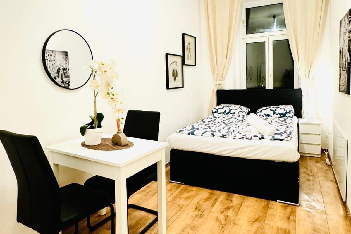 A bedroom with a bed, a desk, a chair, and a window with curtains.