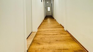 A long, narrow hallway with white walls and a wooden floor. - 5BR Apt For 10 Walk to Kaufpark Alterlaa (Vienna)