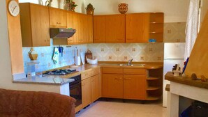 A kitchen with wooden cabinets, a stove, and a dining area with a table and chairs.