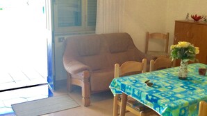 A dining area with a table covered by a blue tablecloth, a wooden chair, and a vase with flowers.