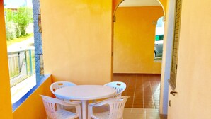 A small balcony with a table and chairs, a tiled floor, and a view of the street.