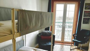 A dormitory room with bunk beds, a chair, and a view of the city through a large window. - Room-4lisbon Downtown Private Bedroom Ci (Lisbon)