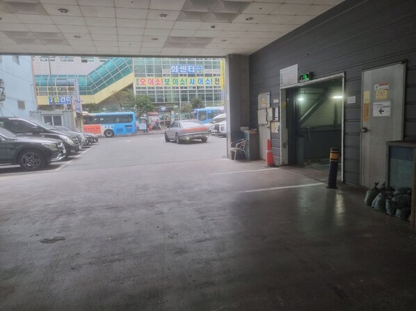 A parking garage entrance with multiple cars and buses, a staircase, and a building with signage in a foreign language. - Noah hotel (Busan)