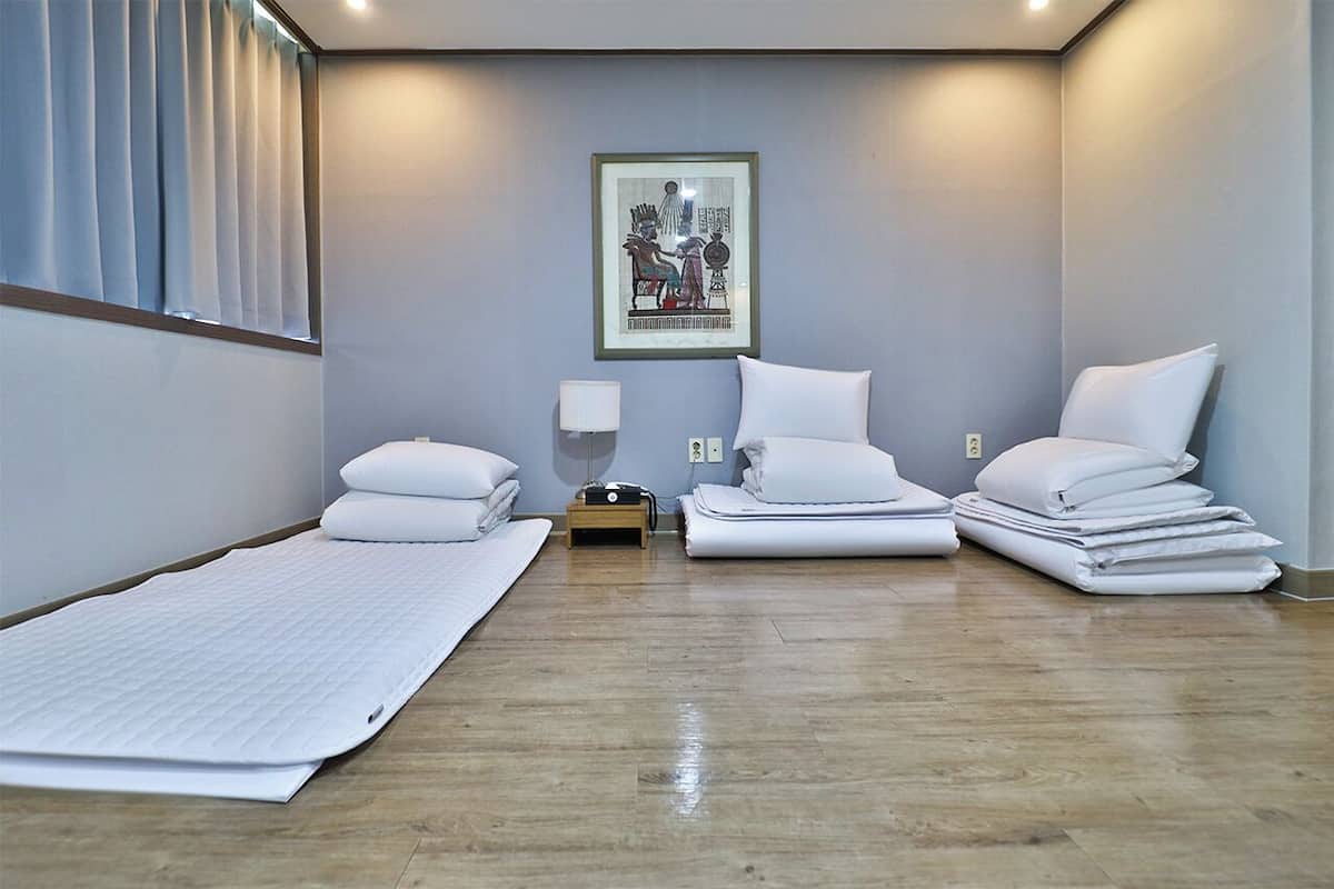 Una habitación de hotel con una cama, una mesita de noche, una lámpara y un cuadro en la pared.