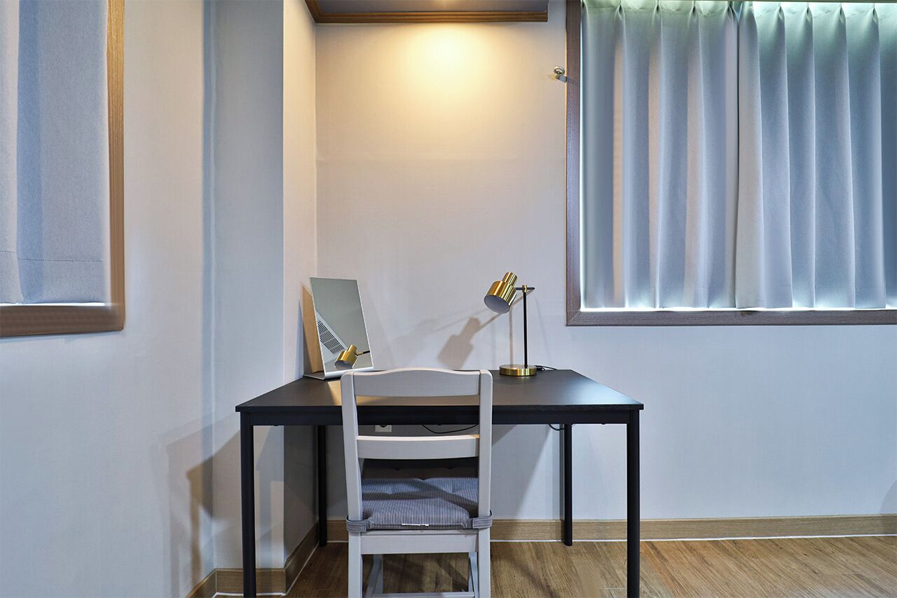 A small, neatly arranged workspace with a desk, chair, and a lamp.