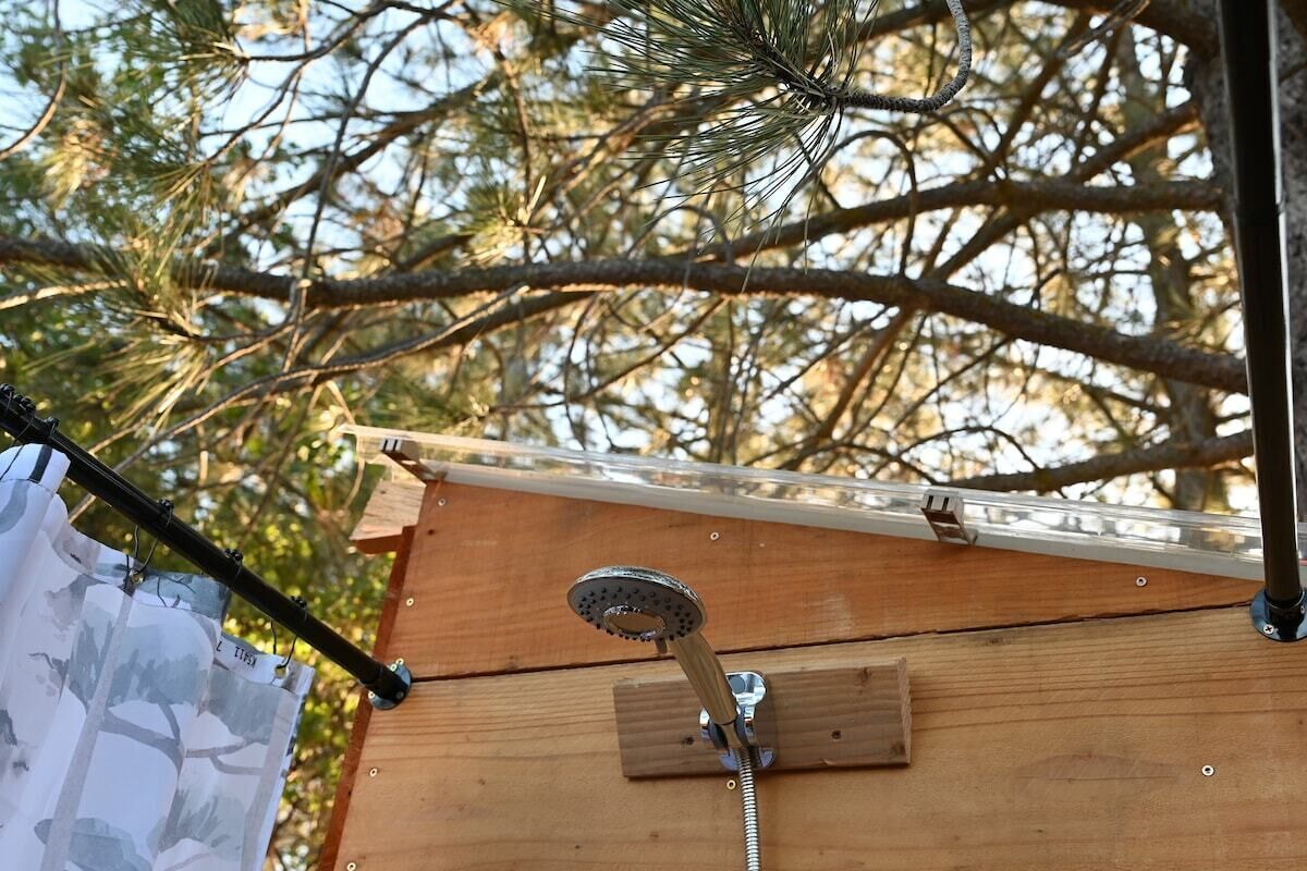 Une structure en bois sur laquelle est fixée une pomme de douche en métal, le tout étant monté sur un mur.