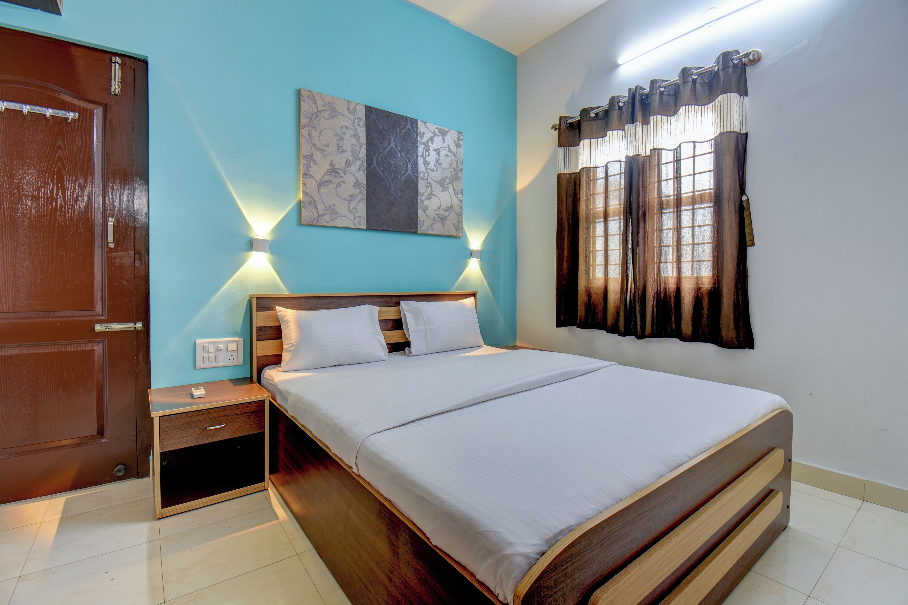 A neatly arranged bedroom with a wooden bed, bedside tables, and a wall-mounted light fixture.