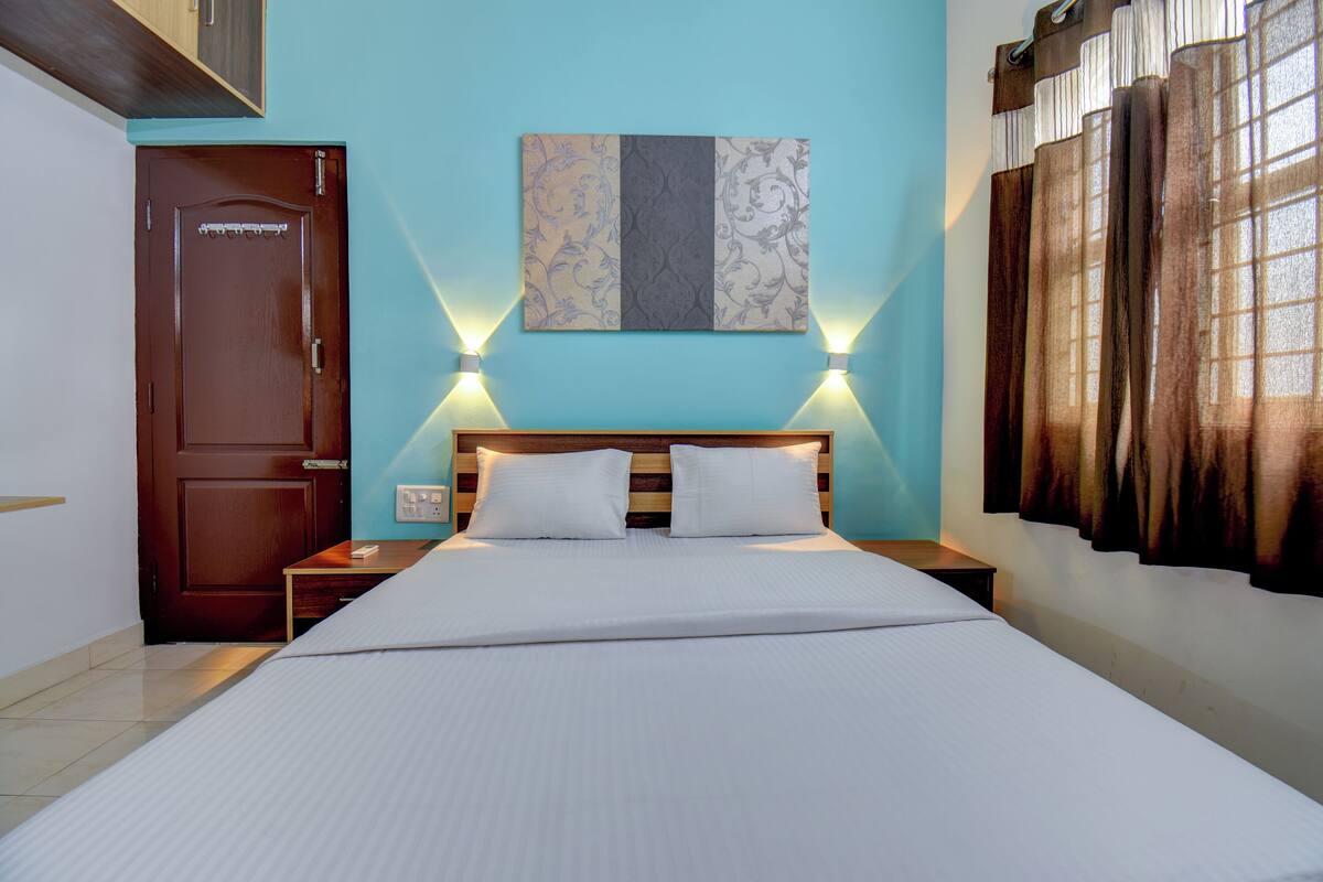 Una habitación de hotel con una cama de madera, dos mesitas de noche, un aparador y una obra de arte colgada en la pared, además de una puerta.