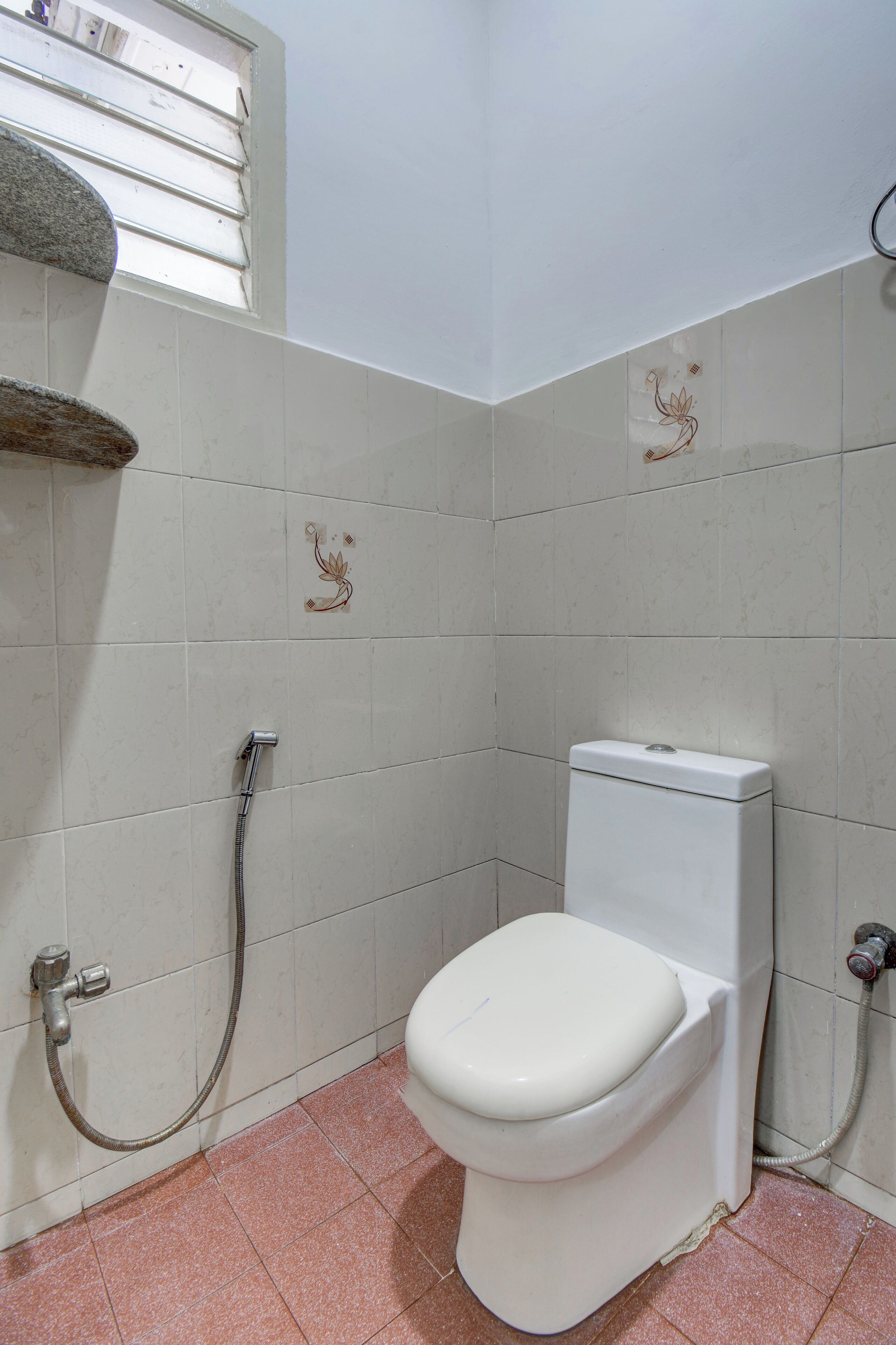 Ein kleines Badezimmer mit Toilette, Dusche und Fenster.