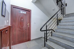 Une porte en bois avec une pancarte, un escalier avec des rampes en métal et un petit bureau.