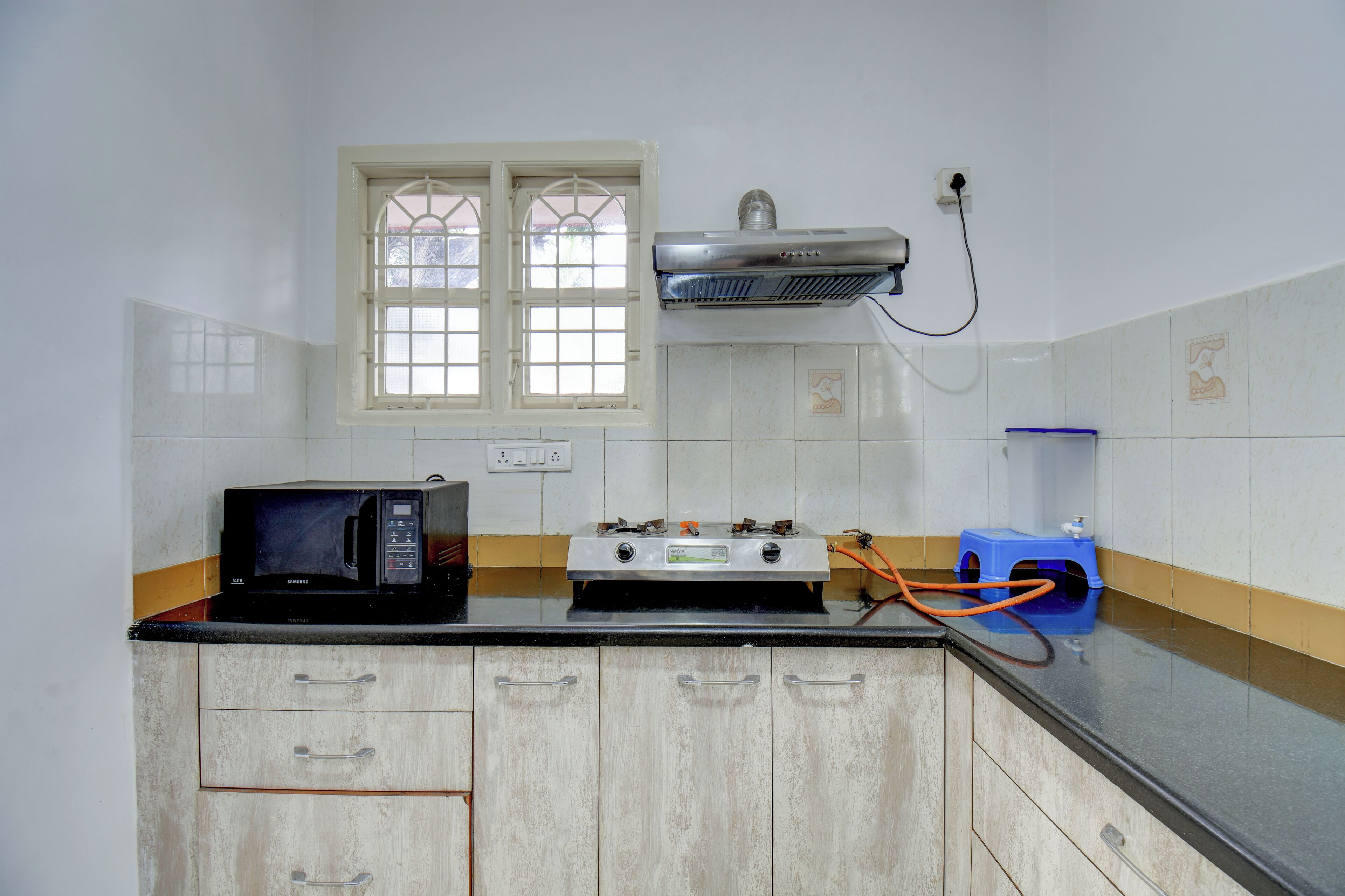 Una cocina equipada con microondas, estufa a gas y dispensador de agua.