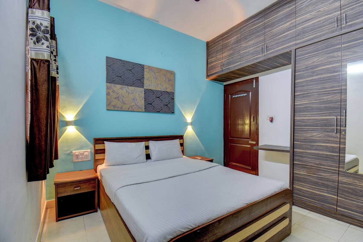Un dormitorio con cama, mesitas de noche, lámpara de pared, armario y un adorno en la pared.